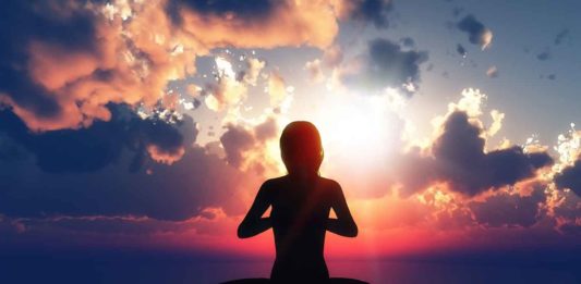 Une femme entre en résonance face à un coucher de soleil.