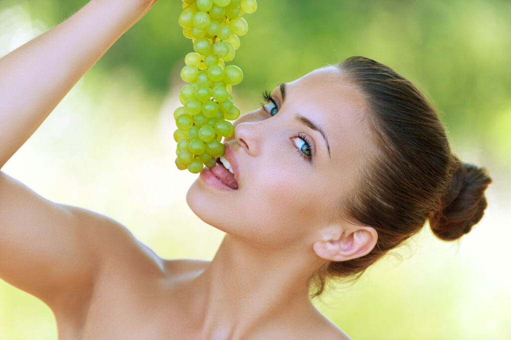une belle femme qui mange une grappe de raisin
