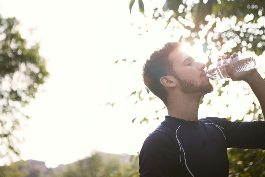 Homme qui boit de l'eau dans une bouteille en PET